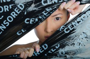East woman peeking in the gap between the black ribbons with the inscription prohibiting