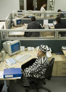Businesswoman at desk in convict's outfit